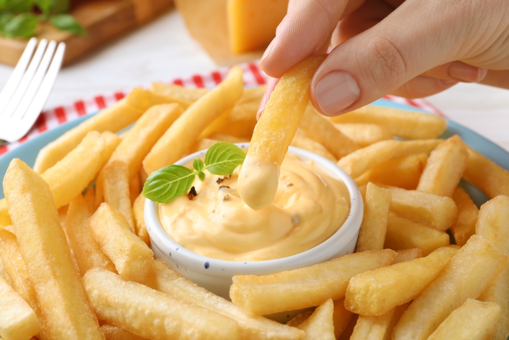 Woman,Dipping,Delicious,French,Fries,Into,Cheese,Sauce,,Closeup