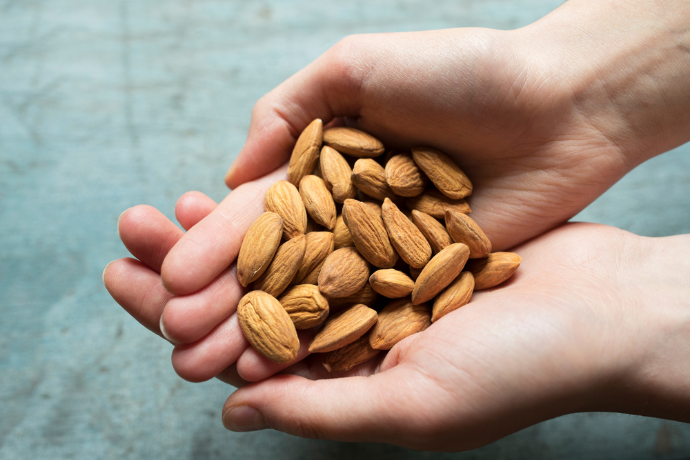 Close,Up,Of,Woman,Holding,Handful,Of,Almonds,Nutrition