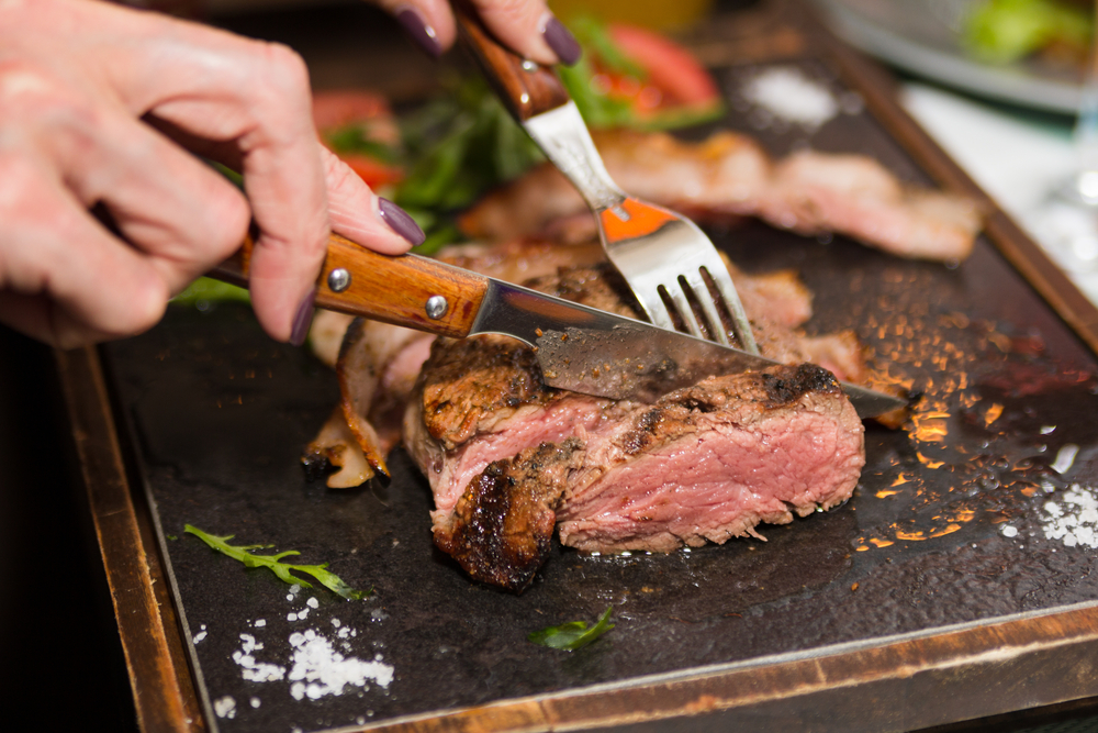 Woman,Hand,Holding,Knife,And,Fork,Cutting,Grilled,Beef,Steak