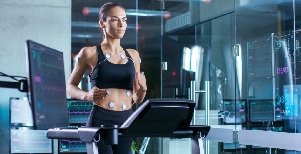 Beautiful,Woman,Athlete,Runs,On,A,Treadmill,With,Electrodes,Attached